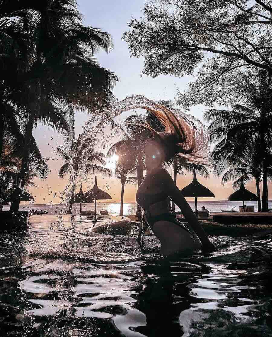 Traveller swimming in the resort lagoon at sunset at Constance Prince Maurice.