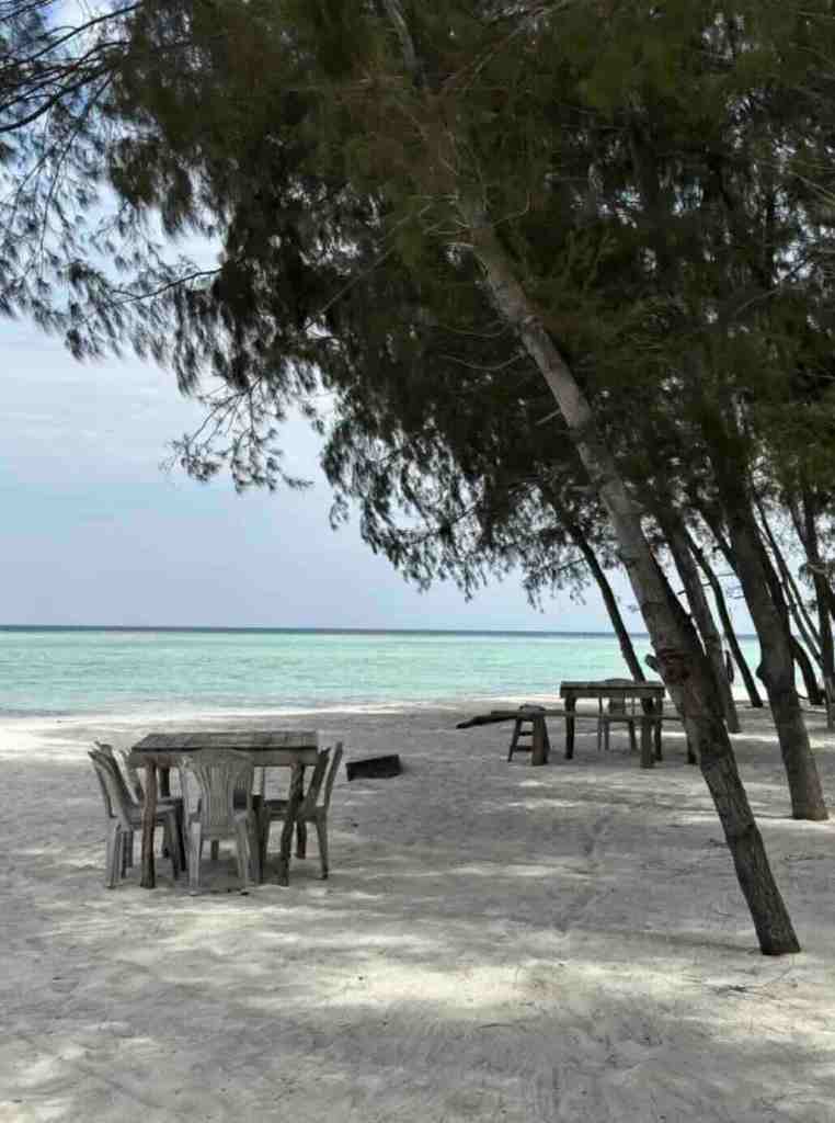 Quiet beach cafe with tables under trees on Gili Asahan, Indonesia
