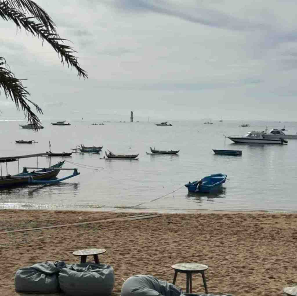 Traditional boats floating in calm water along Sanur Beach in Bali