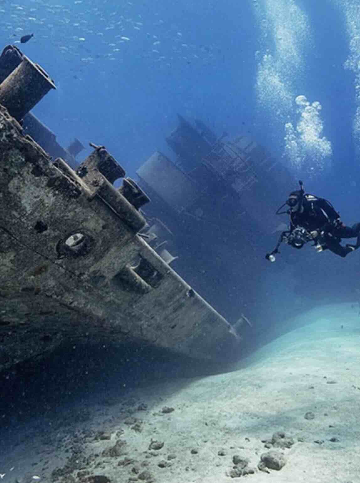 Scuba diver exploring a shipwreck underwater near Amed, Bali