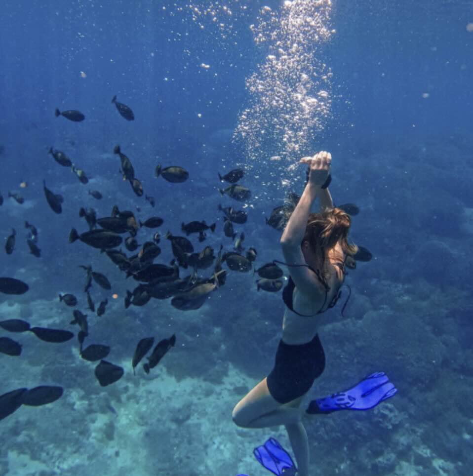 Snorkeler swimming among tropical fish in clear blue water around Nusa Lembongan, Bali.
