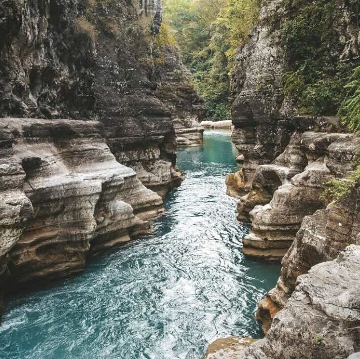 Tanggedu Waterfall in East Sumba with bright blue water flowing through a dramatic rocky canyon.