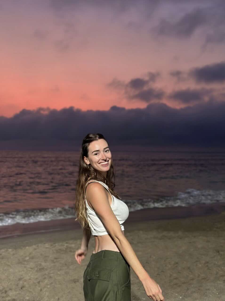 Traveler smiling on Seminyak Beach during a colorful sunset in Bali