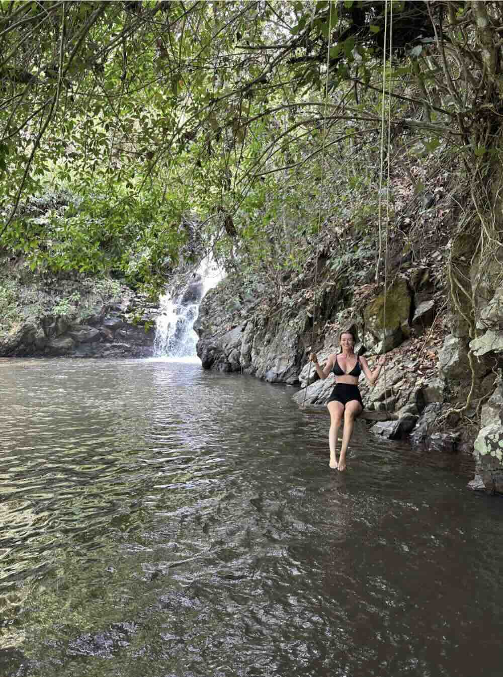 Traveler sitting in a jungle river pool near a waterfall in Munduk, Bali