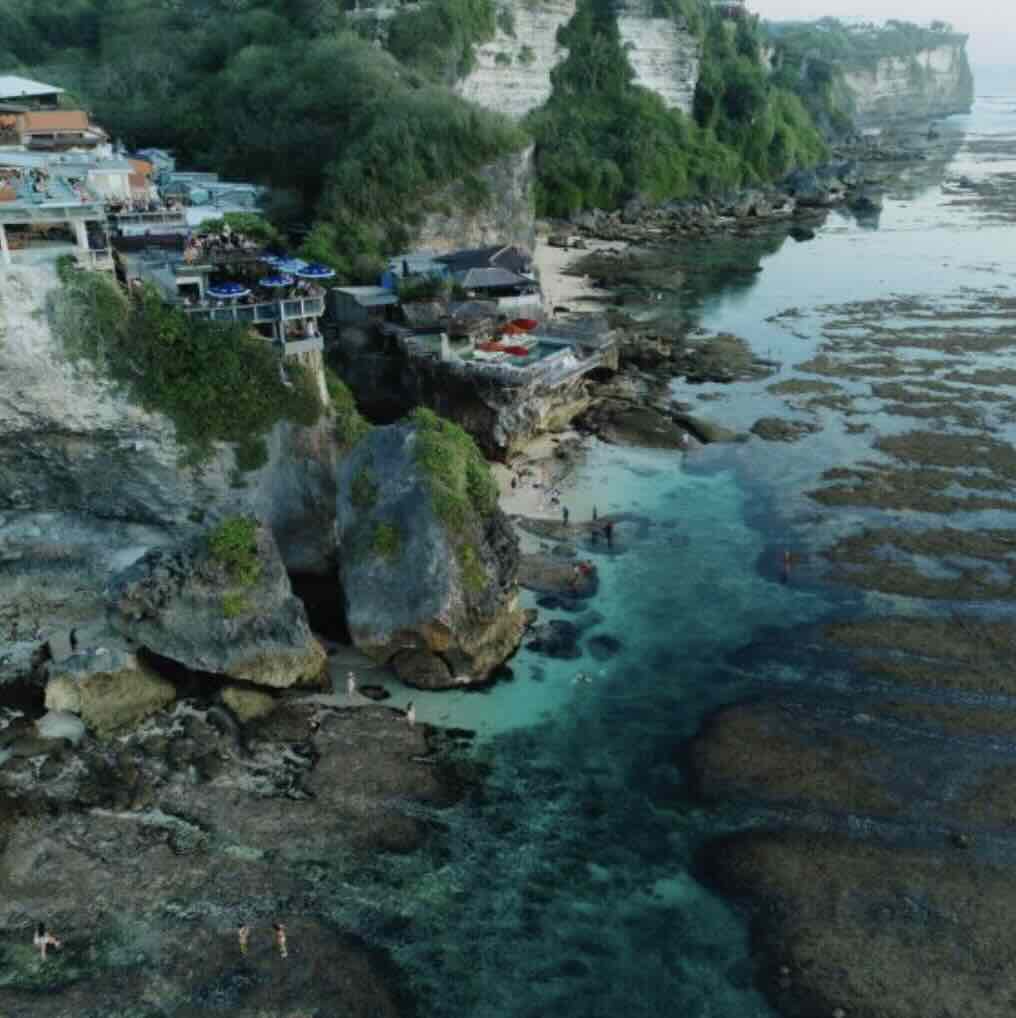 Oceanfront cliff bar overlooking turquoise water and rocky coastline in Uluwatu, Bali