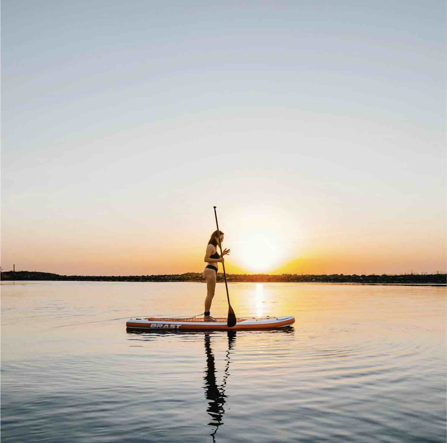 Paddleboarder on calm water during sunrise in Sanur, Bali