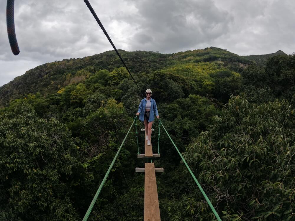 Woman crossing a suspension bridge high above the forest at Casela Nature Parks in Mauritius.