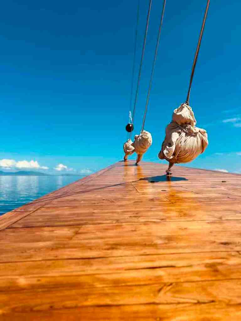 Wooden foredeck and rigging of the MAJ Oceanic Phinisi while sailing through Komodo National Park.