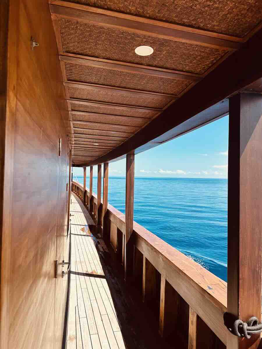 Wooden side deck of the MAJ Oceanic liveaboard with bright blue sea beside the boat.