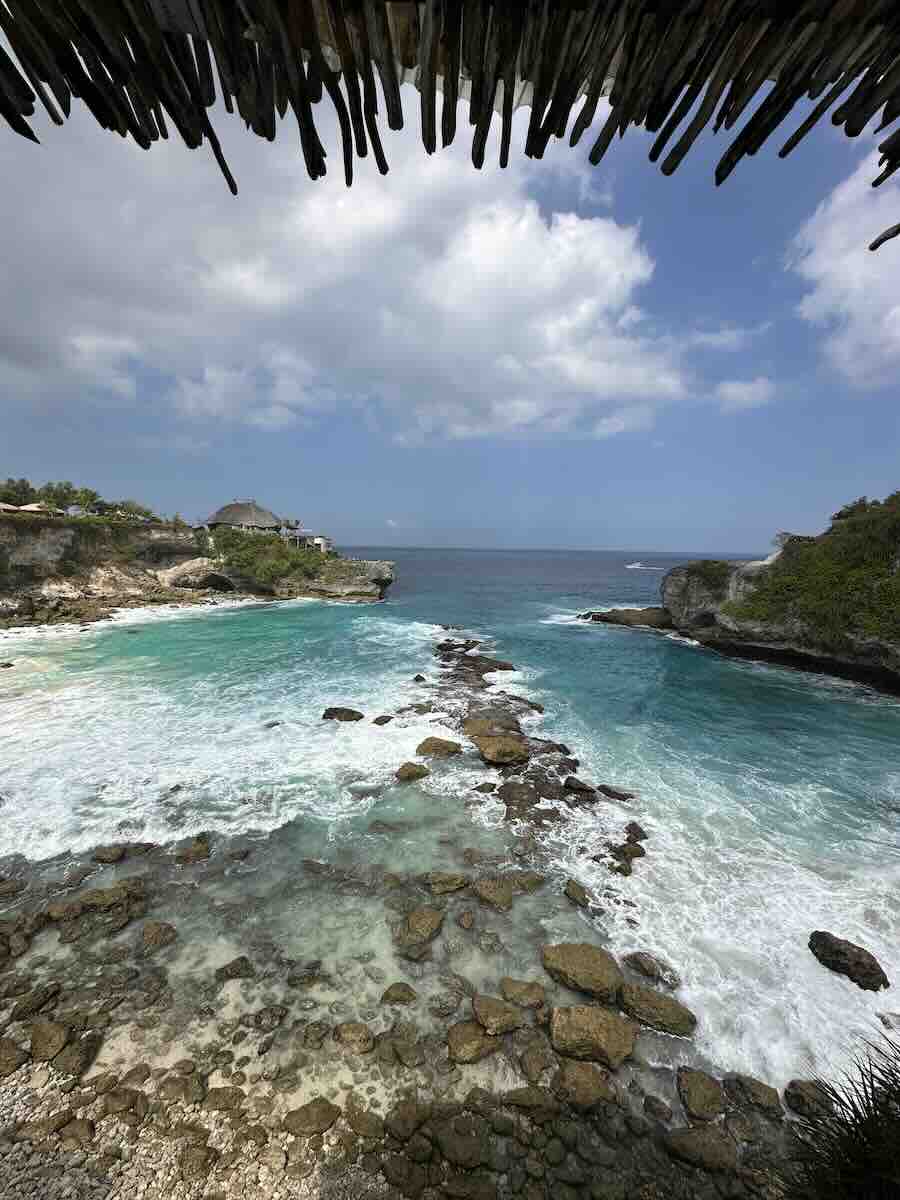 Turquoise ocean water flowing between rugged rocky cliffs of Blue Lagoon along the coast of Nusa Ceningan.