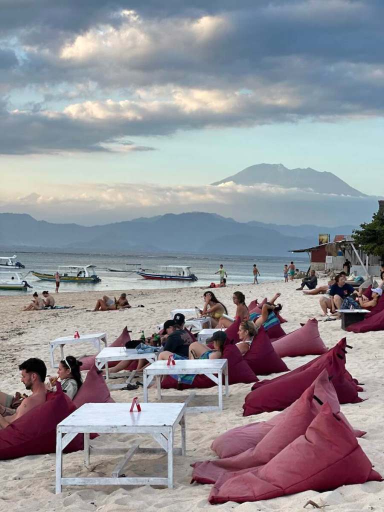 Beachfront beanbags and tables overlooking boats and Mount Agung from Nusa Lembongan, Bali.
