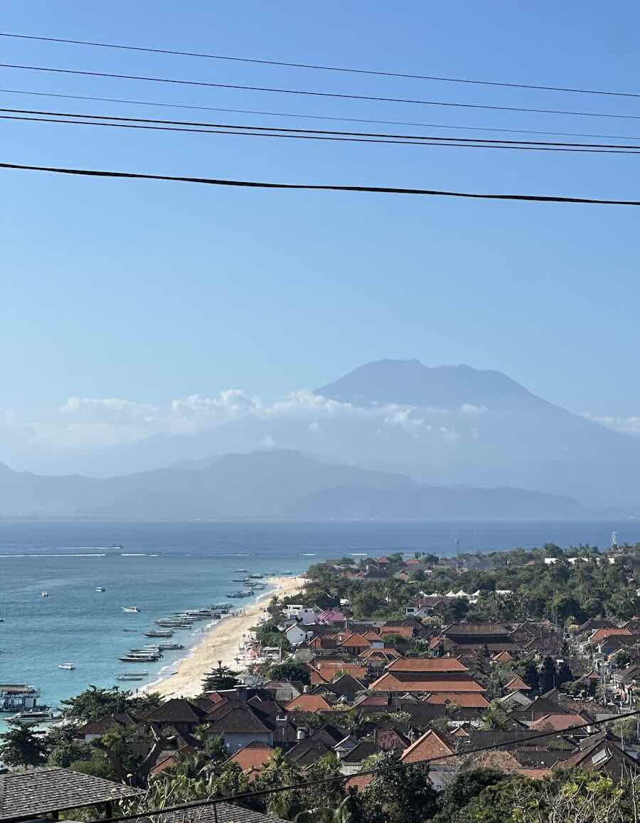Panoramic view over Jungut Batu village and coastline with Mount Agung visible across the sea from Nusa Lembongan.