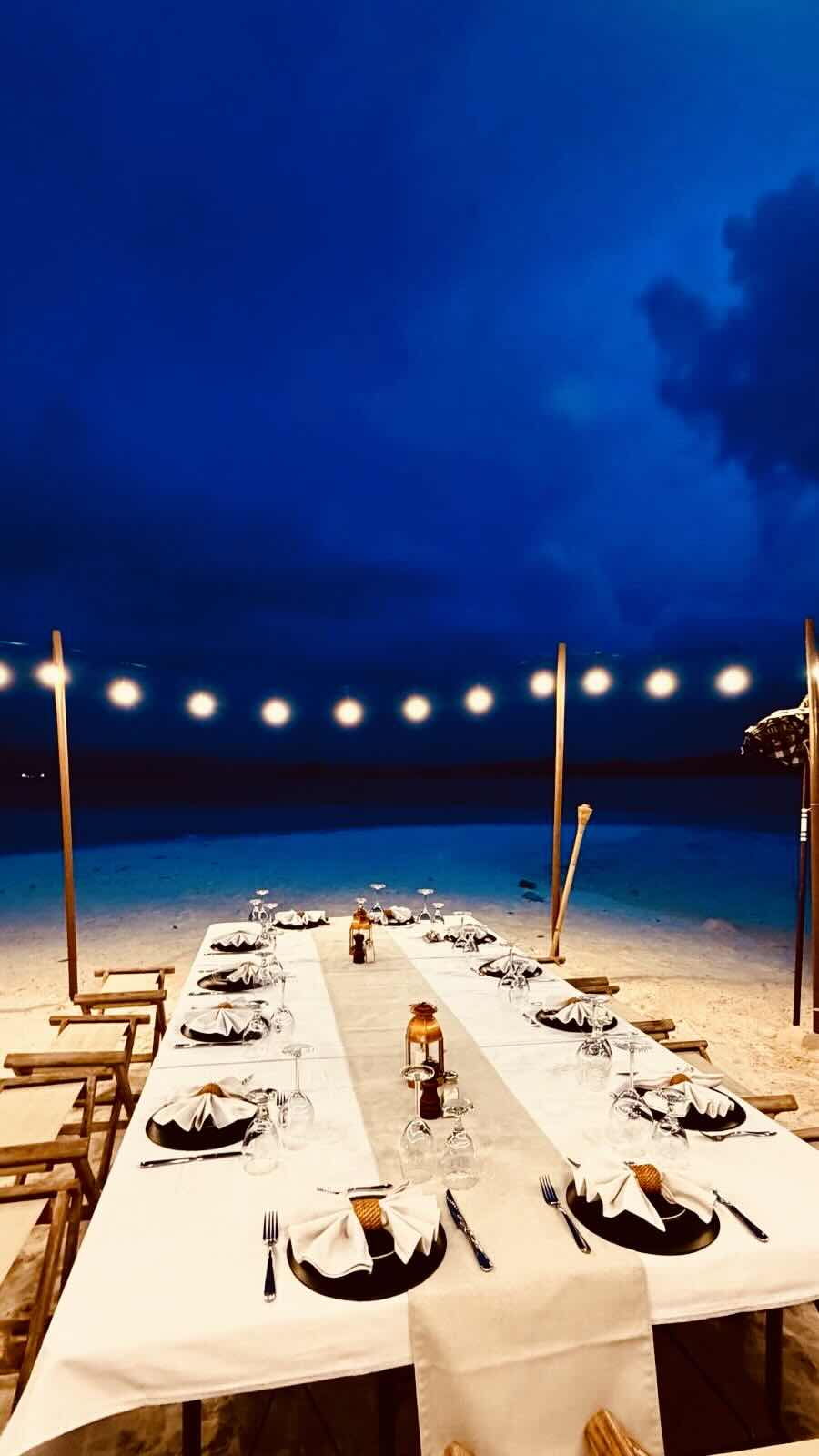 Private beach dinner with string lights set up on Papanga Island during a Komodo liveaboard charter.