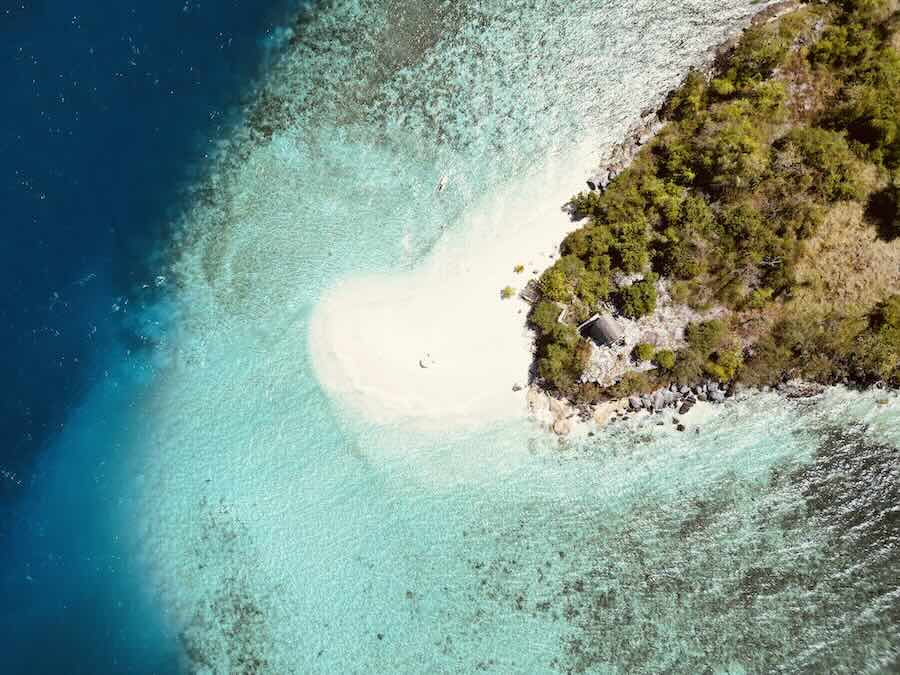 Aerial view of a small white-sand beach and clear turquoise water at Papanga Island.
