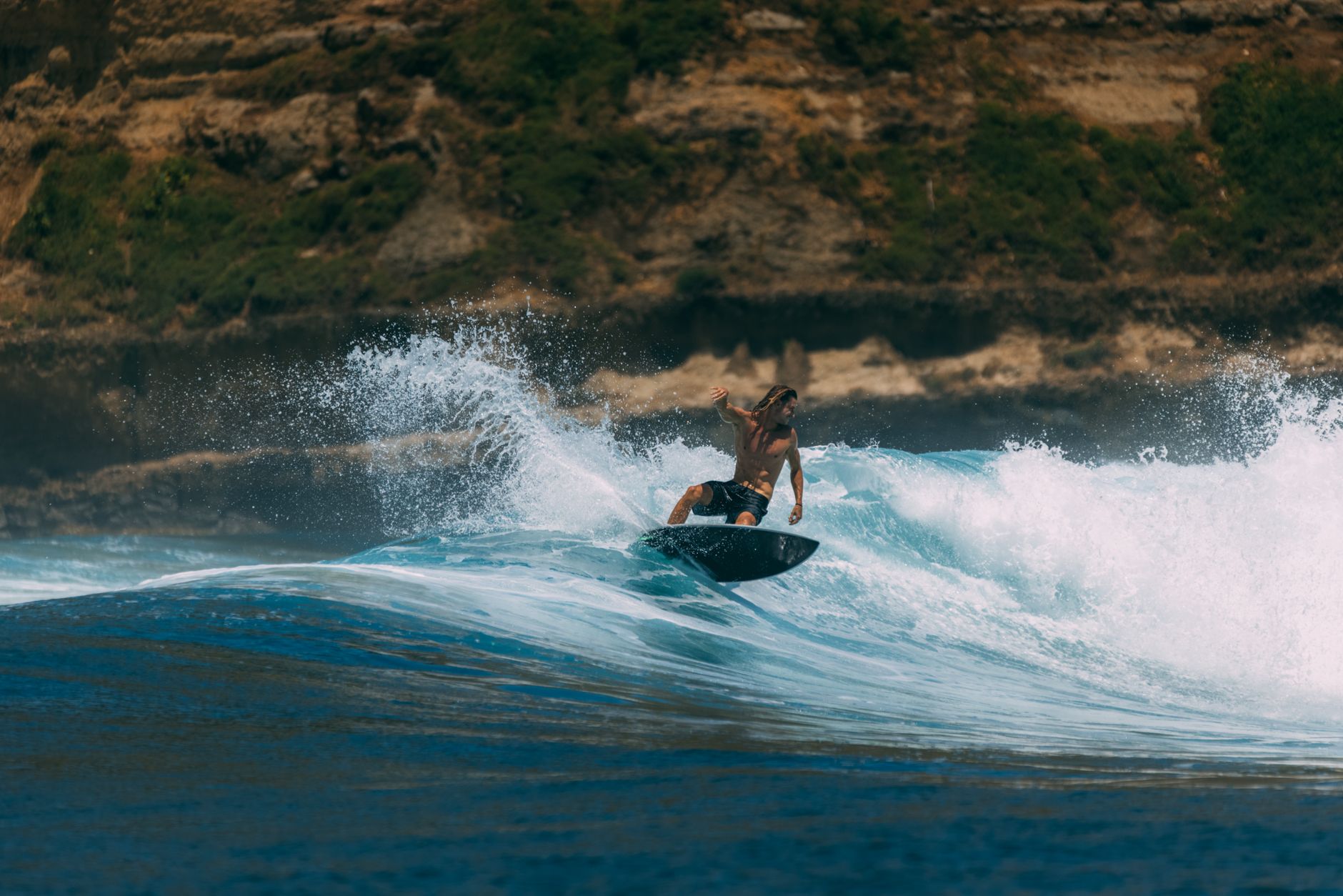 Surfer riding a wave off the coast of Rote Island, Indonesia