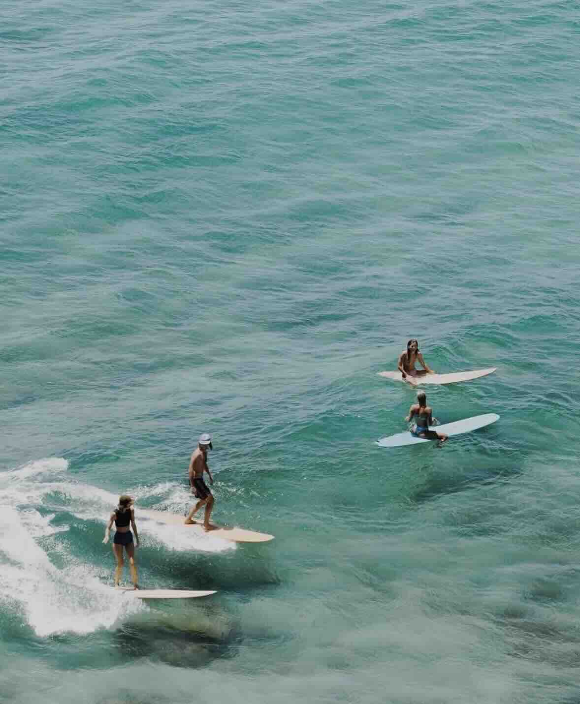 Surfers riding clear turquoise waves off the coast of Sumba, Indonesia