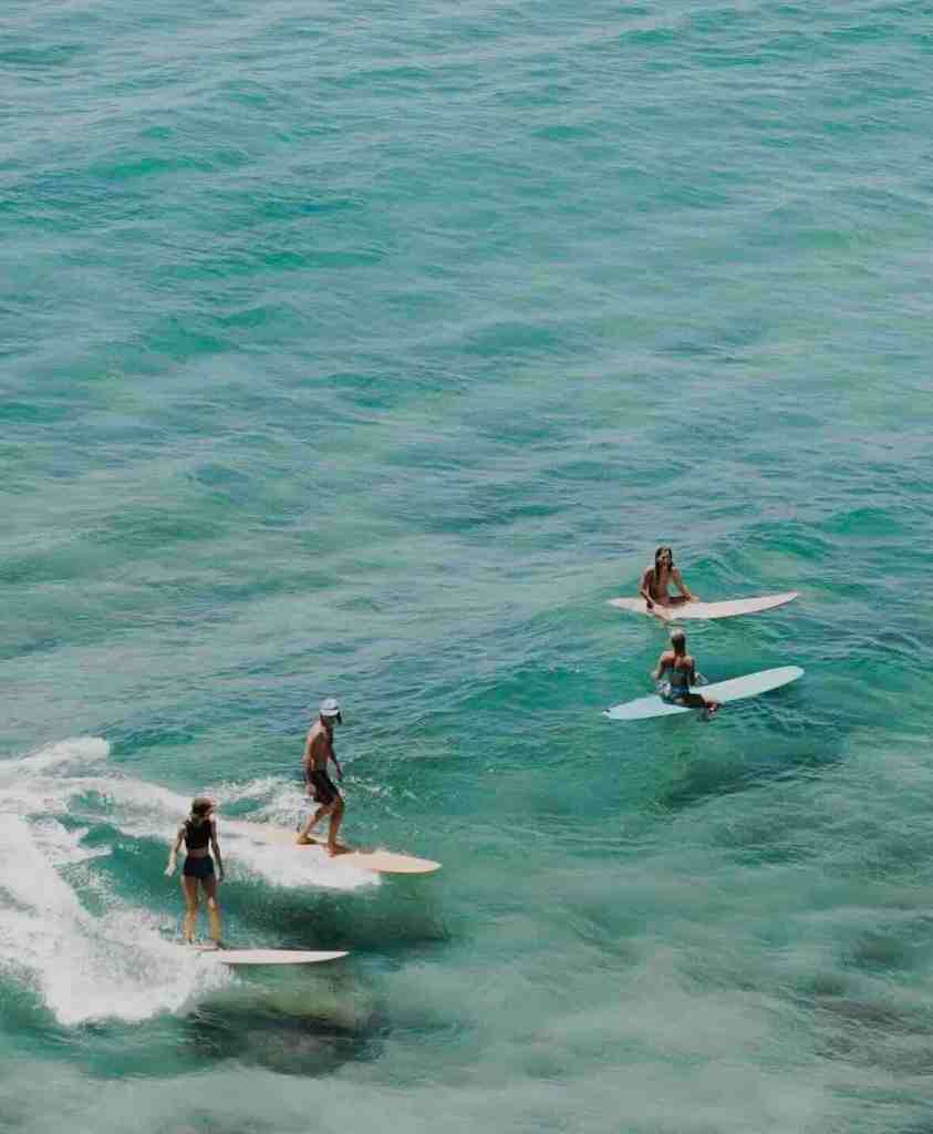 Surfers riding clear turquoise waves off the coast of Rote, Indonesia