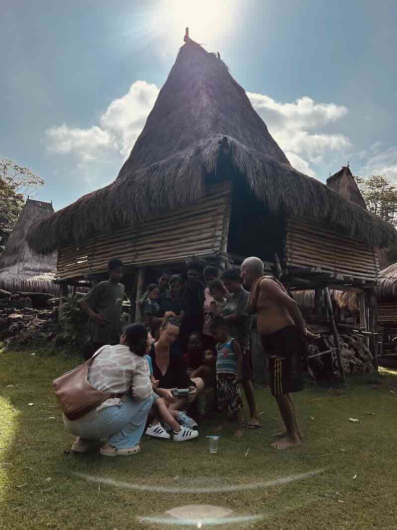 Visitor meeting local families outside a traditional house in Prai Ijing Village, West Sumba.