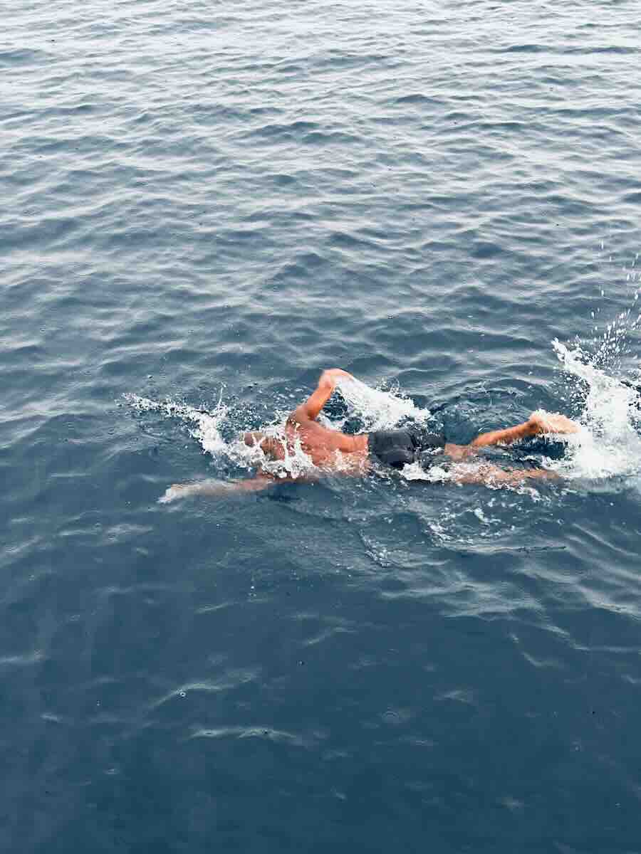 Traveler swimming in open blue water near Taka Makassar in Komodo National Park.