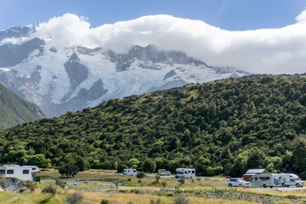 Campervans at White Horse Hill Campground beneath the snow-covered mountains of Aoraki Mount Cook National Park.