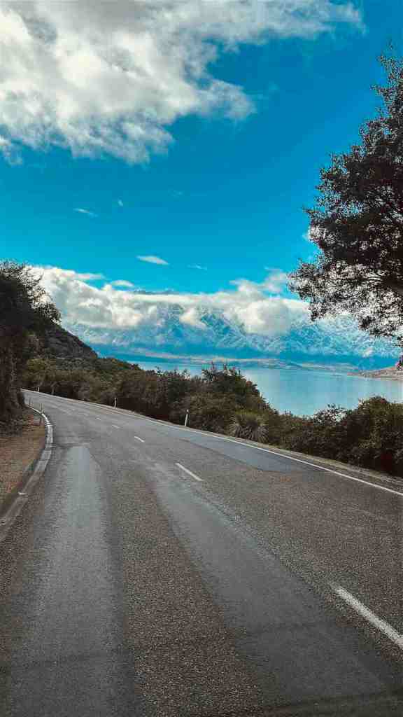 Lakeside road running beneath bright blue sky between Queenstown and Glenorchy.