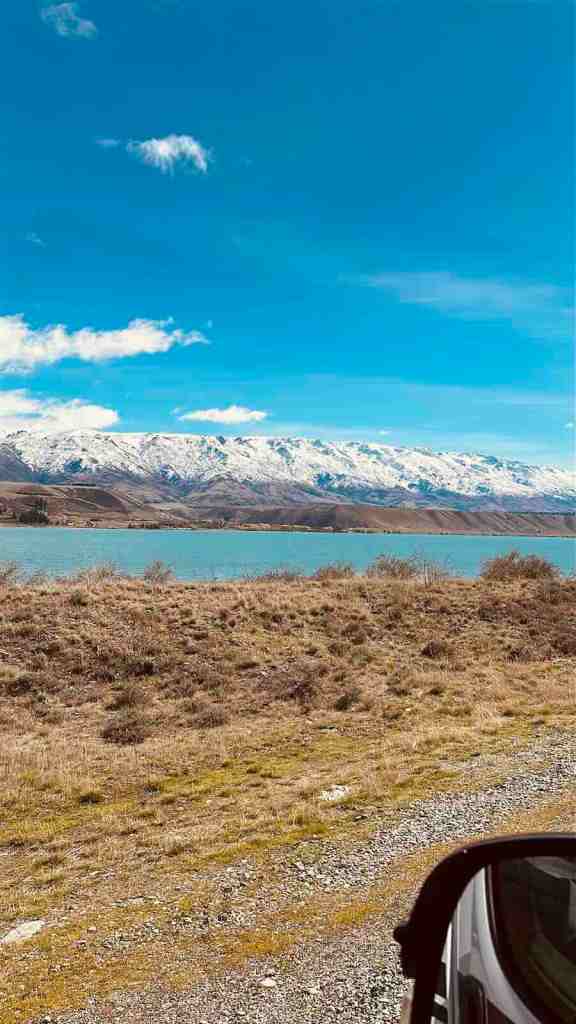 Dry Central Otago landscape with blue water and snow-capped mountains in the distance.