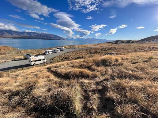 Campervans parked beside Lake Pukaki beneath a bright blue sky during our South Island road trip.