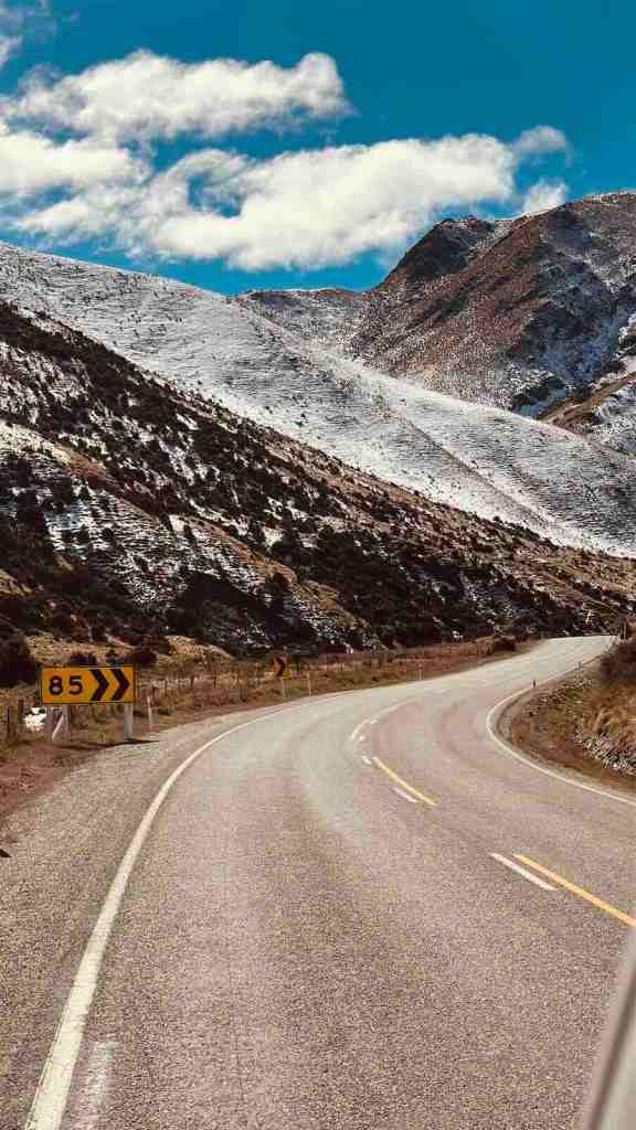 Winding section of SH8 curving between dry alpine mountains at Lindis Pass.