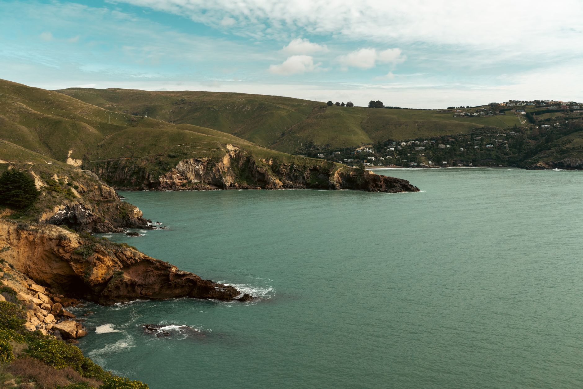 Turquoise Lyttelton Harbour surrounded by green coastal hills on Banks Peninsula near Christchurch.