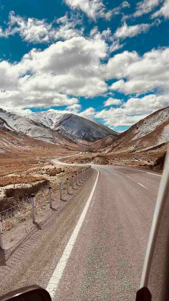 A winding road through the mountains of New Zealand’s South Island, surrounded by snow-covered peaks during our September campervan road trip.