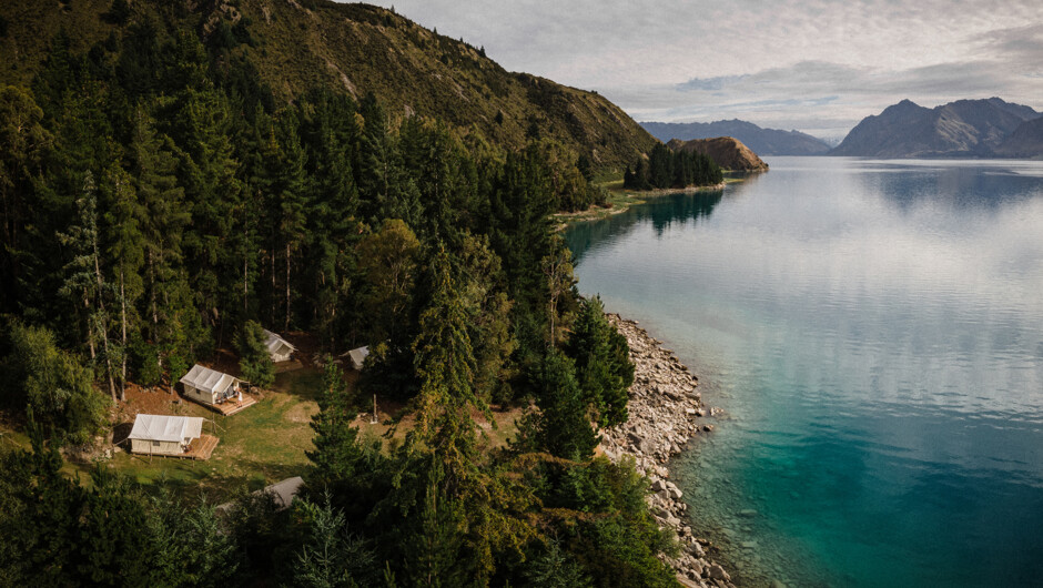 Peaceful lakeside campground surrounded by forest and mountains during our New Zealand campervan trip.